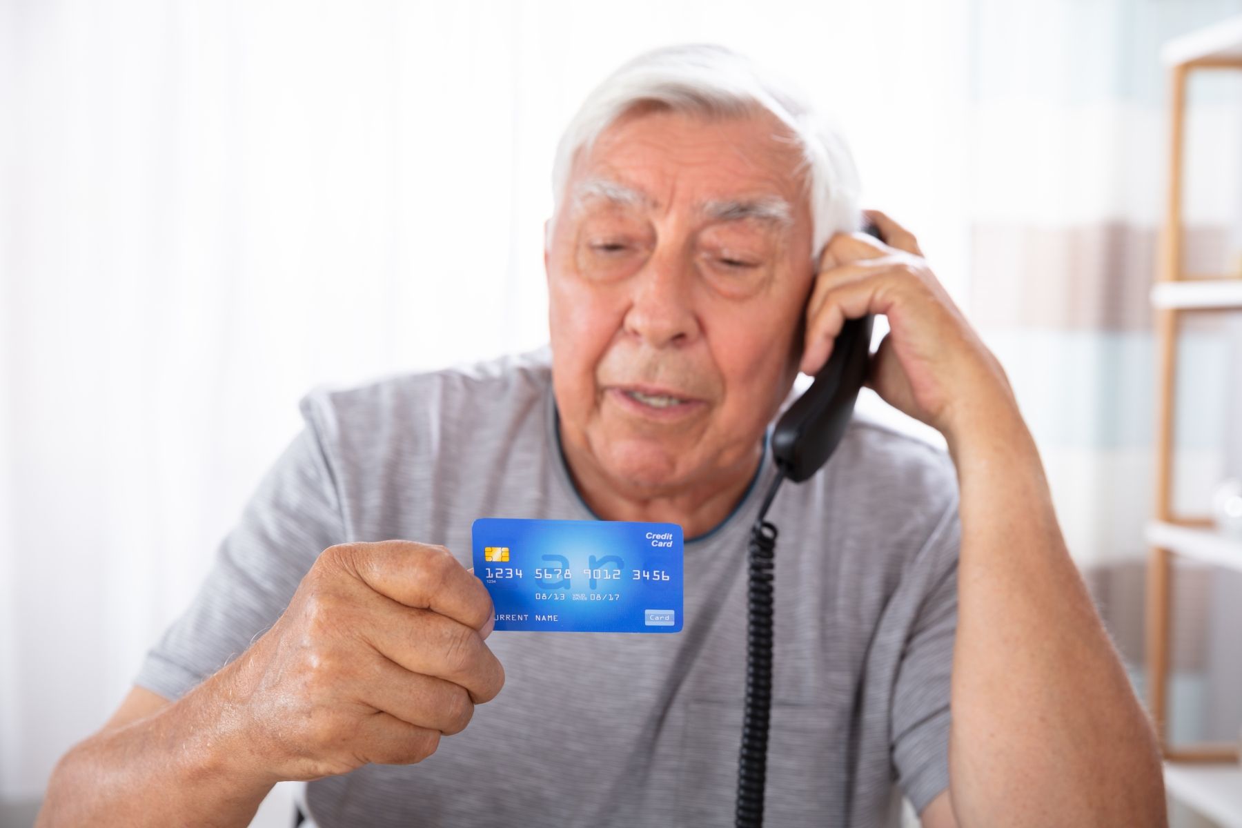 Man som pratar i telefon och tittar på ett kreditkort