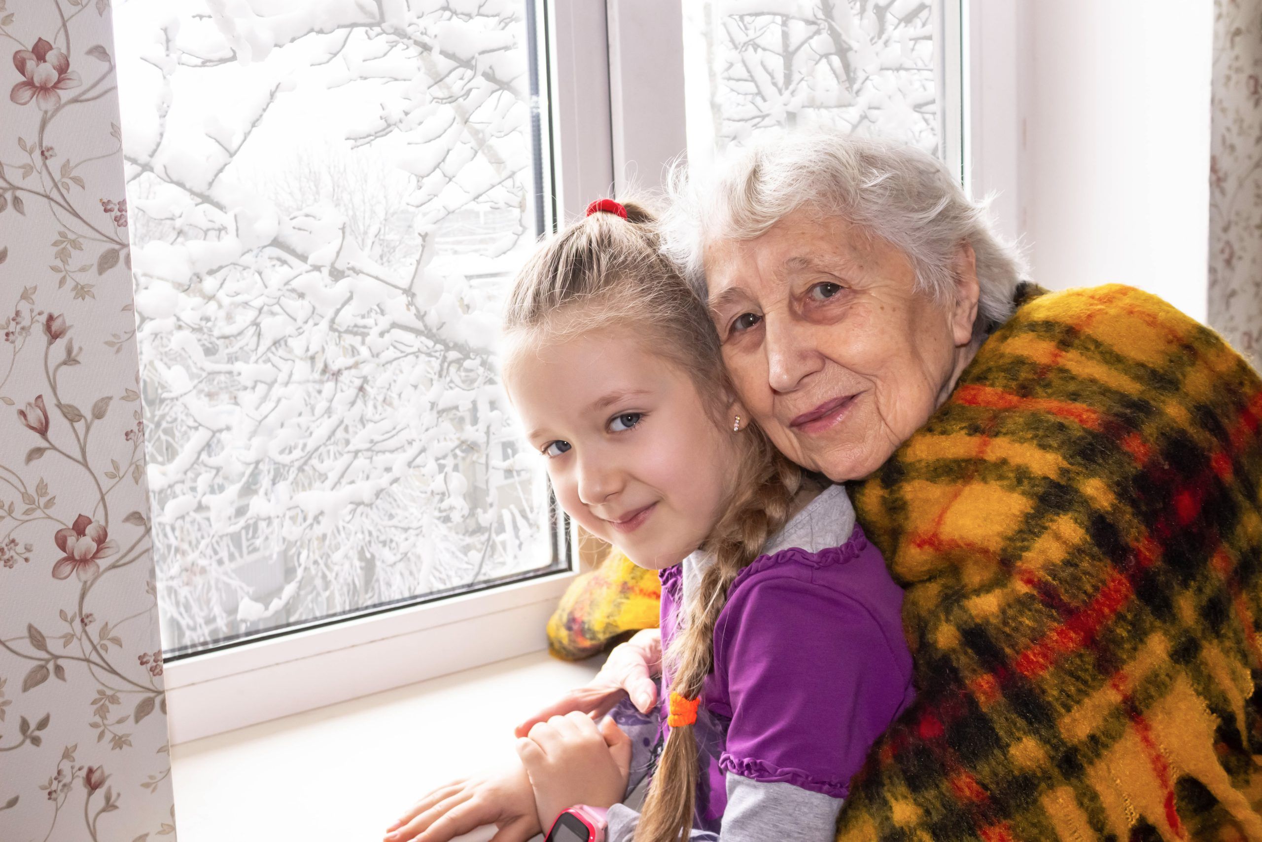 En äldre kvinna och en flicka framför ett fönster