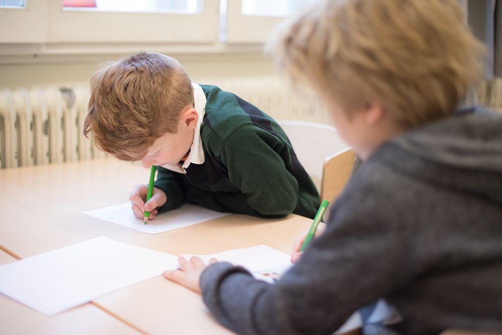 Två barn som sitter lutade över en bok