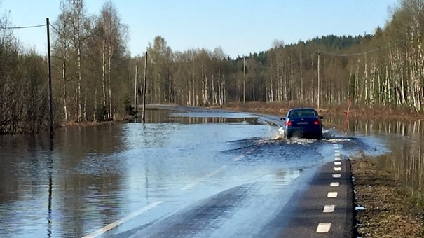 En bil som kör på en väg med högt vattenflöde
